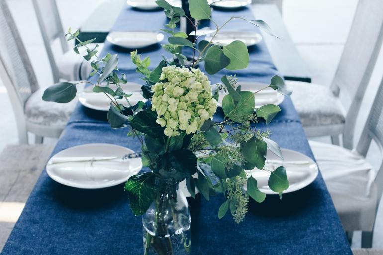 Table set with plates, flowers, and blue tablecloth